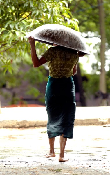 woman walking in the rain with a large pan on her head