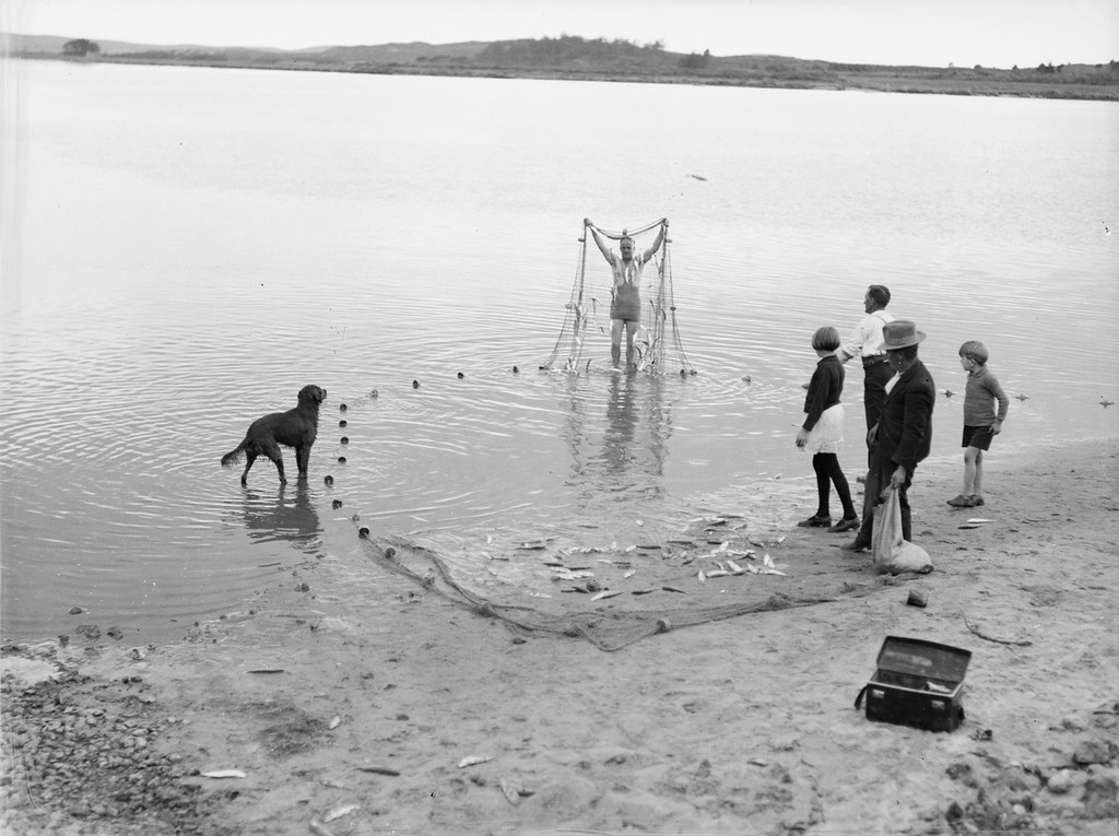 [Group of people on shoreline with fishing net]