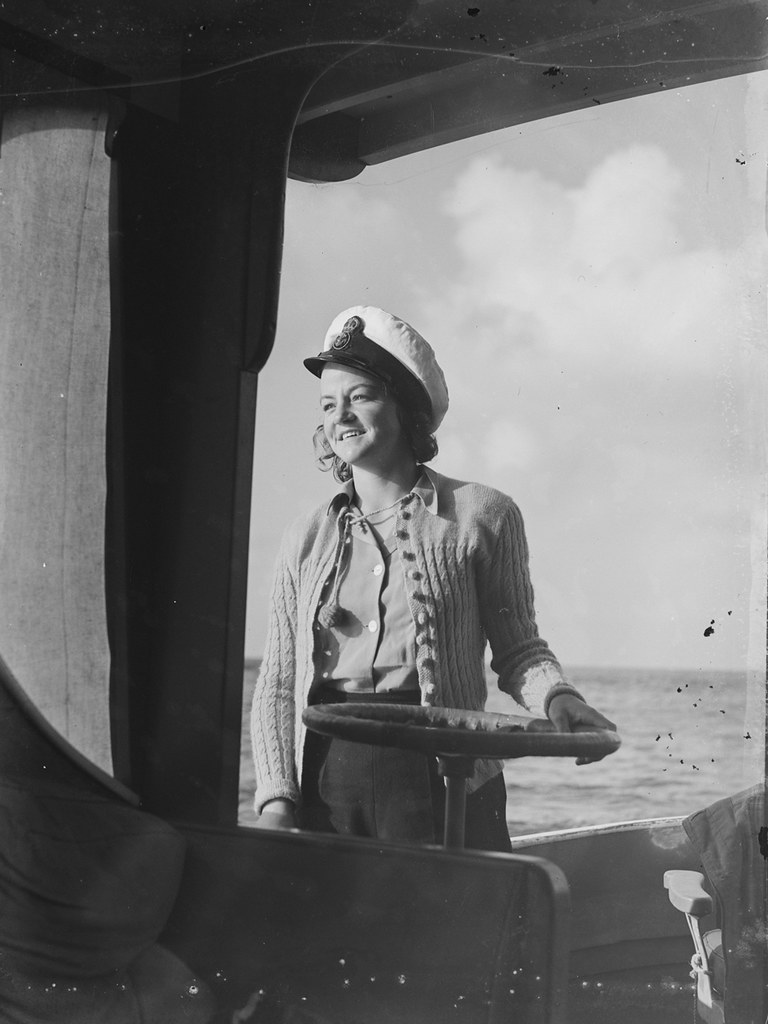 [Woman wearing Naval cap standing on a boat]