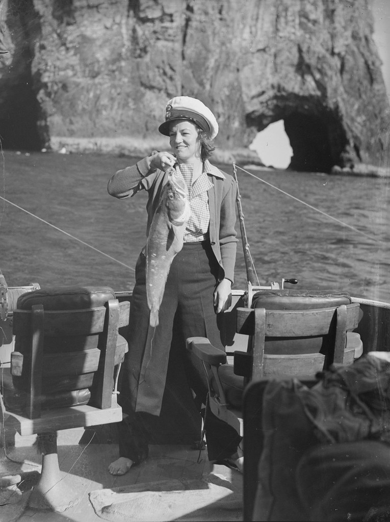 [Woman wearing a naval cap holding a fish]